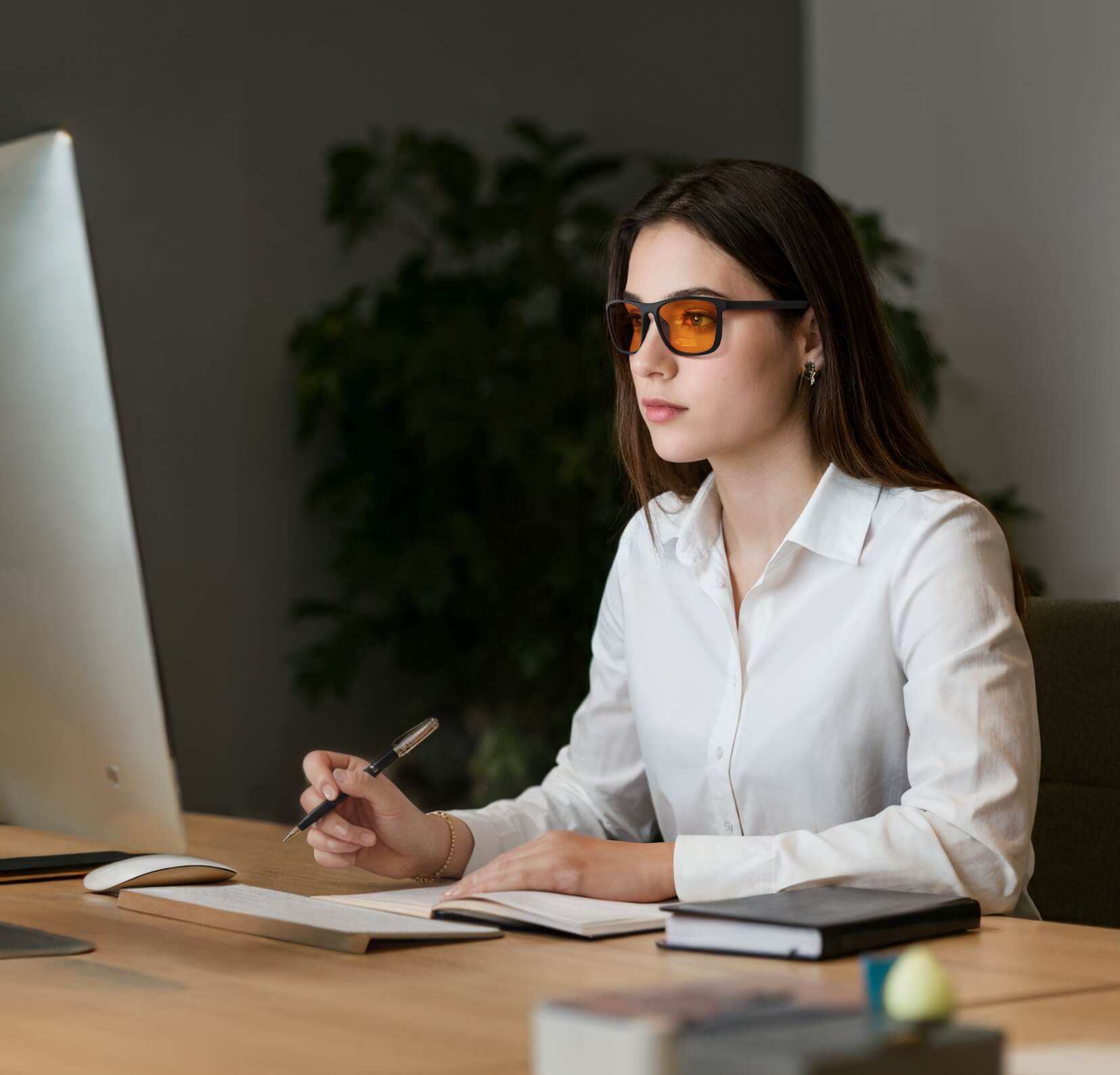 a young white lady is working in office and on talking with wearing night ease wayfarer sleep glasses with black frame