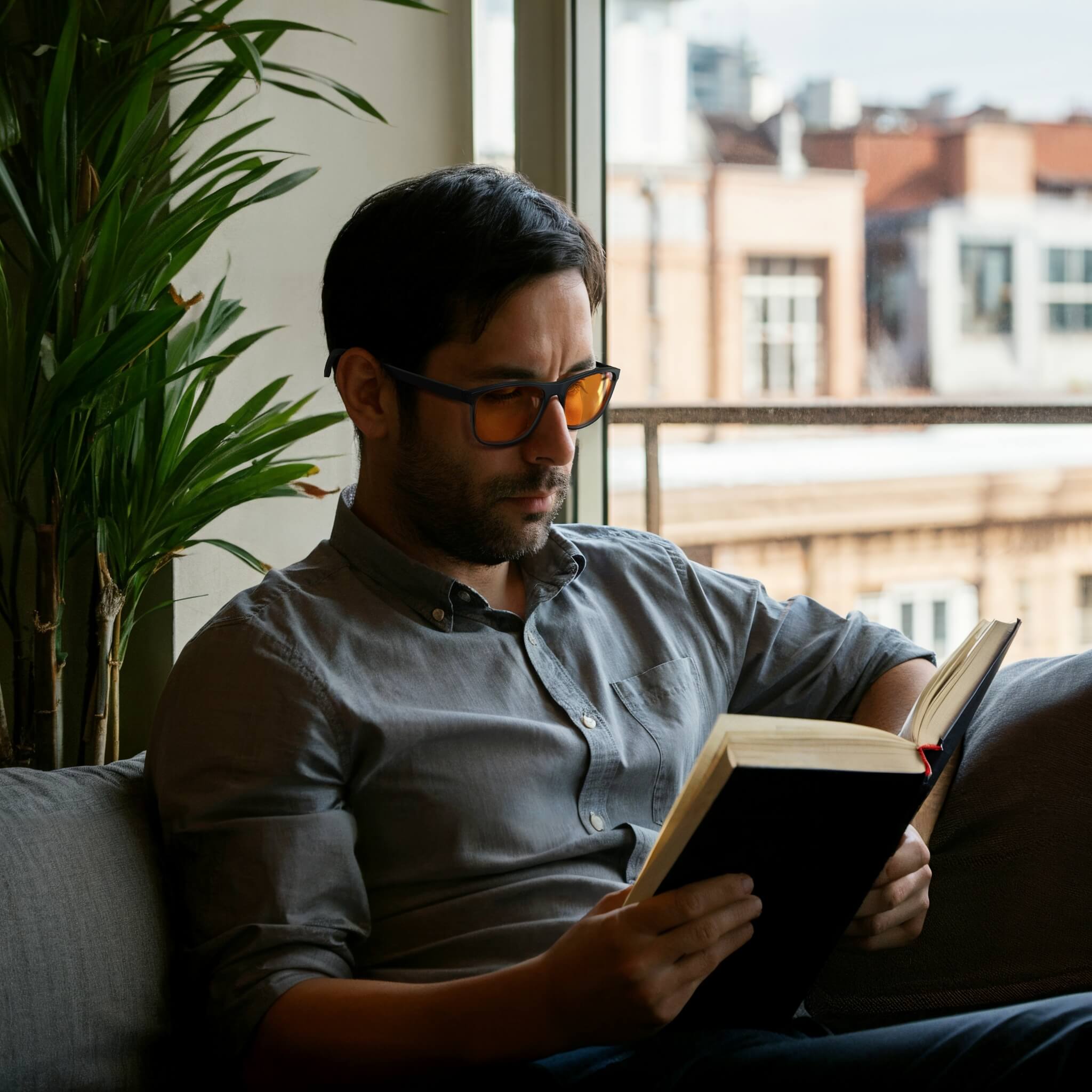 an elegant man is reading books at home with wearing night ease rectangle sleep glasses with black frame which helf him to relax and concentrate