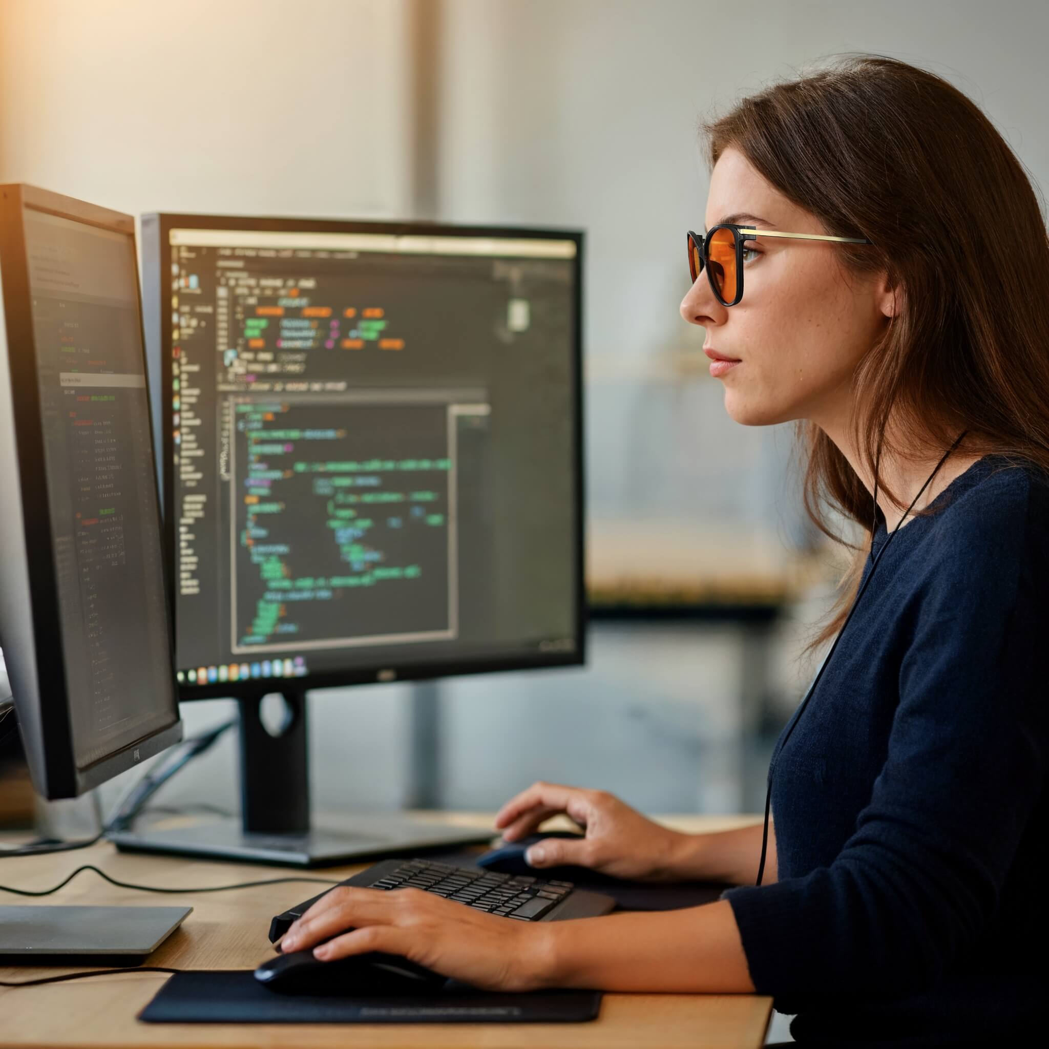 a fermale programmer is working with wearing night ease cat eye sleep glasses with black gold frame to release her eye fatigue