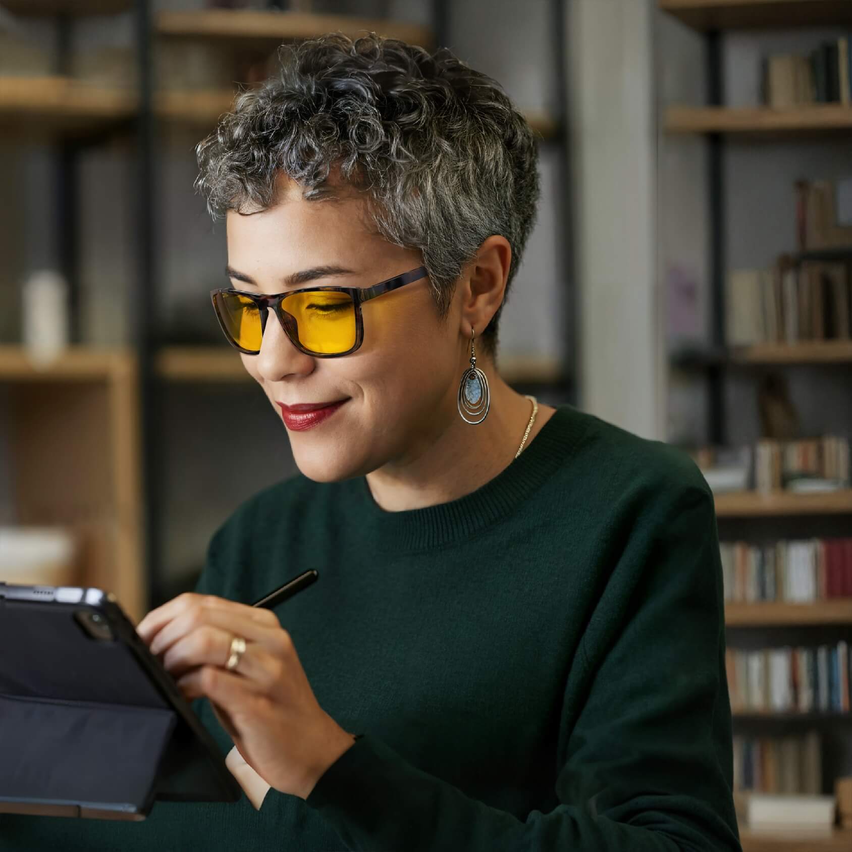 an old woman is wearing amber shield wayfarer light sensitivity glasses with tortoiseshell frame for using tablets